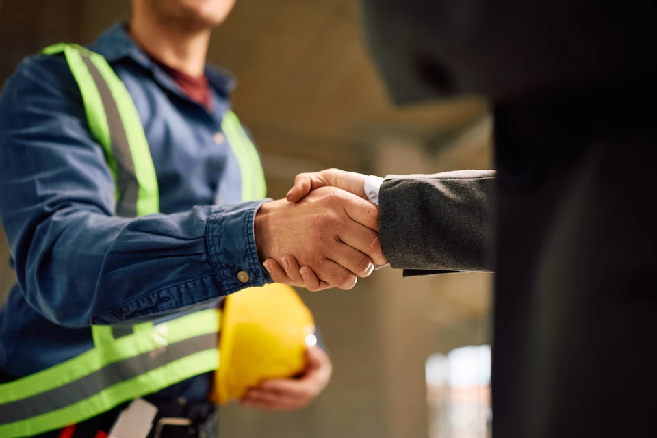 Diagnostiqueur immobilier portant un polo professionnel et équipé d'outils de diagnostic (humidimètre, thermocaméra ou testeur), inspectant les murs intérieurs et les fondations visibles d'un logement ancien, en évaluant l'état général de la structure et les risques potentiels.